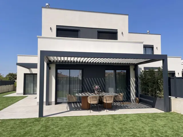 Pérgola adosada a la fachada de una casa unifamiliar contemporánea